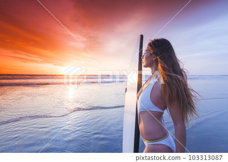 Surfer woman on beach at sunset Surfer woman on beach at sunset 103313087
