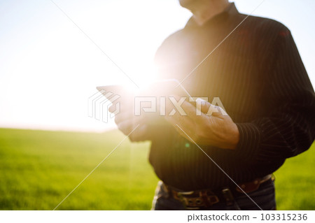 Owner farm using touch pad for check wheat quality in the field. Agronomist standing in wheat field. Owner farm using touch pad for check wheat quality in the field. Agronomist standing in wheat field. 103315236