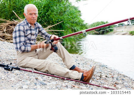 Aged man fishing at lakeside 103315445