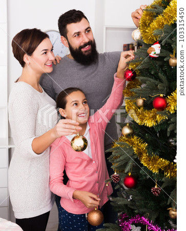 Family putting decorations on Christmas tree 103315450