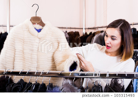 Female customer examining white mink jacket Female customer examining white mink jacket 103315493