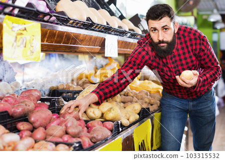 Young male seller offering potatoes Young male seller offering potatoes 103315532