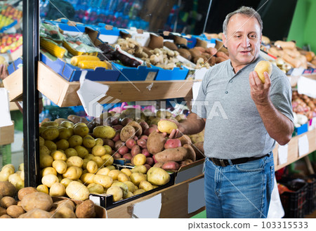 Adult man is choosing potato in the store Adult man is choosing potato in the store 103315533
