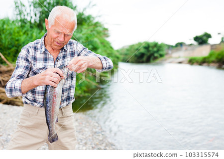 Adult fisherman removing catch from hook 103315574