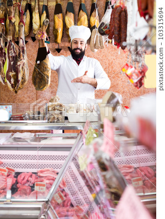 Male shop assistant demonstrating jamon Male shop assistant demonstrating jamon 103315694