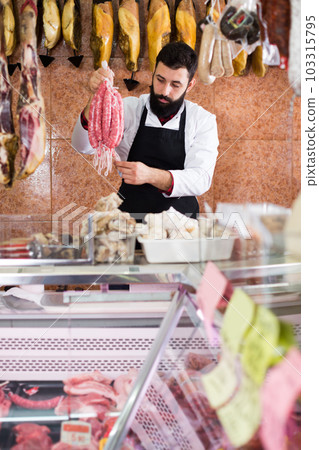 Male seller offering delicious sausages 103315795