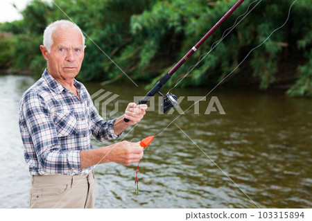 Mature man angling at riverside Mature man angling at riverside 103315894