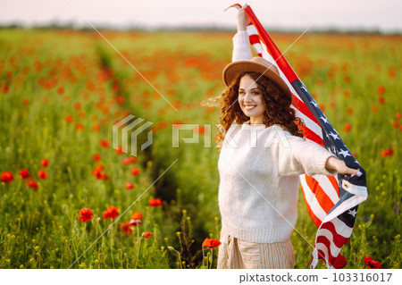 Young woman hold waving american USA flag in in the poppy field. Independence Day, 4th July. Young woman hold waving american USA flag in in the poppy field. Independence Day, 4th July. 103316017