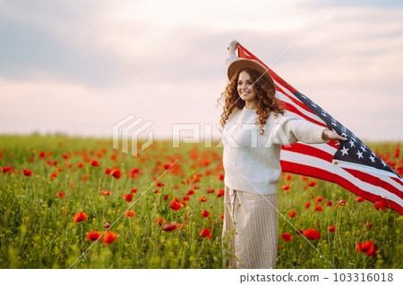 Young woman hold waving american USA flag in in the poppy field. Independence Day, 4th July. 103316018