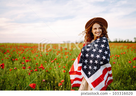 Young woman hold waving american USA flag in in the poppy field. Independence Day, 4th July. Young woman hold waving american USA flag in in the poppy field. Independence Day, 4th July. 103316020