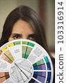 A female fashion designer holds flower samples in her hands, choosing a fabric of blue shades of textiles in the workplace, a dressmaker or tailor, a close-up view 103316914