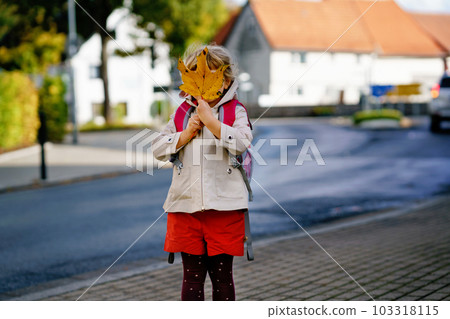 Cute little toddler girl on her first day going to playschool. Healthy happy child walking to nursery school. Kid with backpack going to day care on the city street, outdoors Cute little toddler girl on her first day going to playschool. Healthy happy child walking to nursery school. Kid with backpack going to day care on the city street, outdoors 103318115