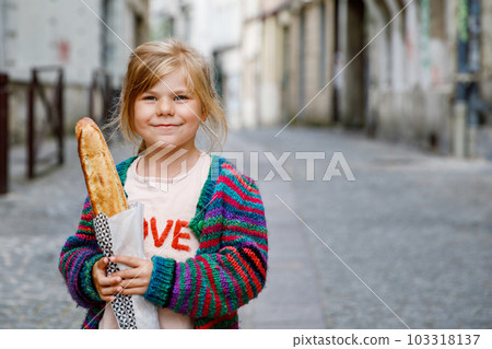 Adorable little preschool girl with fresh French baguette on the street side of the city. Happy small child in Paris, France. Adorable little preschool girl with fresh French baguette on the street side of the city. Happy small child in Paris, France. 103318137