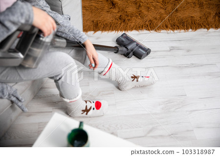 After vacuuming the room for a long time, the girl sits on the sofa and relaxes. 103318987