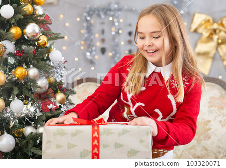 Little girl holding gift boxes near Christmas tree Little girl holding gift boxes near Christmas tree 103320071