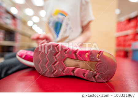 pair of worn out children's sneakers with scuffs damaged straps. 103321963