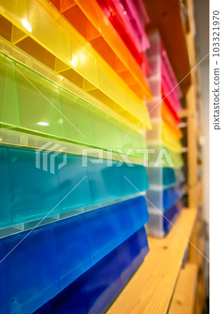 Rows of multi-colored storage bin totes in a retail store shelving space. 103321970
