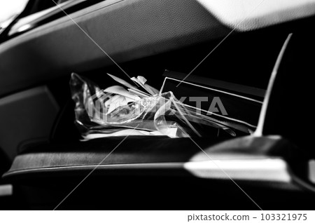 Unorganized mess inside an open glove compartment of a vehicle  103321975