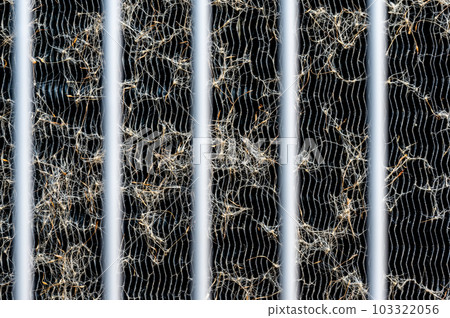 Macro of seed pods and dust collecting on the heat exchanger coils of an air conditioner outside. Macro of seed pods and dust collecting on the heat exchanger coils of an air conditioner outside. 103322056