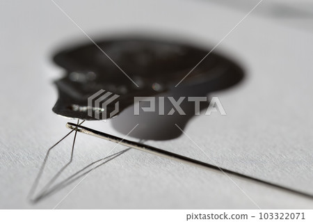 Sewing needle threader tool in use and a single black string. Sewing needle threader tool in use and a single black string. 103322071