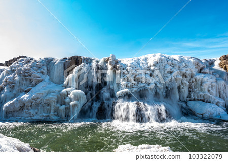 Sioux Falls Park waterfall with ice and snow. Cascading snowmelt water pouring over the top into a pool of standing water. 103322079