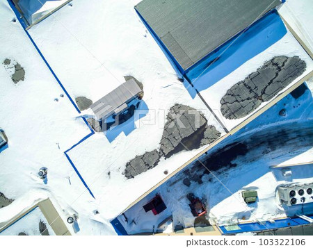 Elevated overhead drone view of a flat roofed building with snow load and ventilation units. Elevated overhead drone view of a flat roofed building with snow load and ventilation units. 103322106