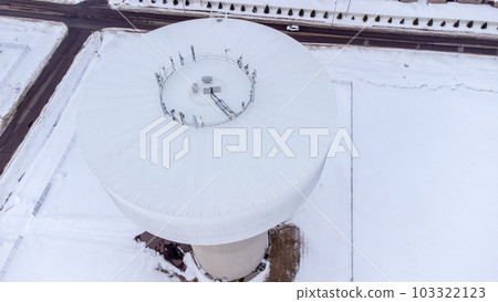Drone overhead view of a water tower with communications antennae mounted on top  103322123