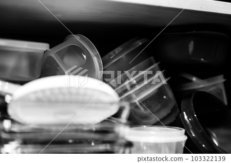 Narrow depth of field picture of an open kitchen cabinet with an assortment of containers and mismatched lids stacked. Narrow depth of field picture of an open kitchen cabinet with an assortment of containers and mismatched lids stacked. 103322139
