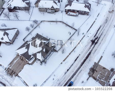 Aerial drone view of a snow covered suburban residential neighborhood with rows of white roofs and houses. Aerial drone view of a snow covered suburban residential neighborhood with rows of white roofs and houses. 103322208