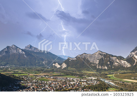 Panorama of the city of Bad Ragaz against the background of the Swiss Alps at sunset with lightning strike. Bad Ragaz Switzerland. Aerial view. Top view. Panorama of the city of Bad Ragaz against the background of the Swiss Alps at sunset with lightning strike. Bad Ragaz Switzerland. Aerial view. Top view. 103323925