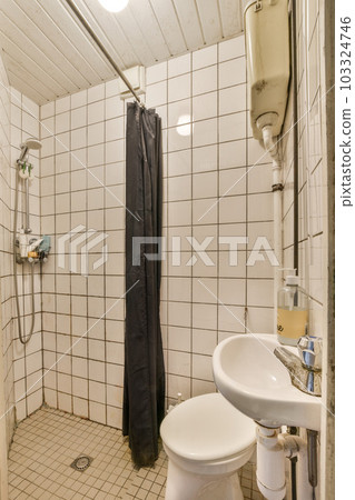 a bathroom with white tiles on the walls and black shower curtain hanging over the toilet in the corner next to the sink a bathroom with white tiles on the walls and black shower curtain hanging over the toilet in the corner next to the sink 103324746