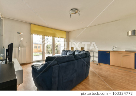 a living room with wood flooring and blue couch in front of sliding glass door that leads out to patio 103324772