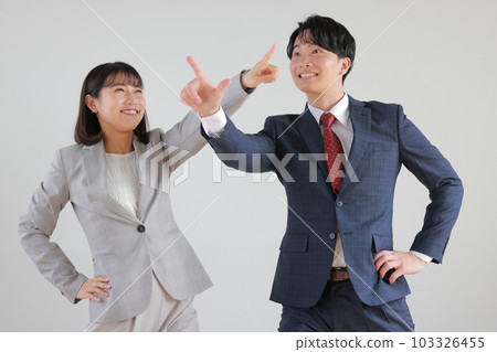 Business woman and businessman pointing in different directions_1 103326455
