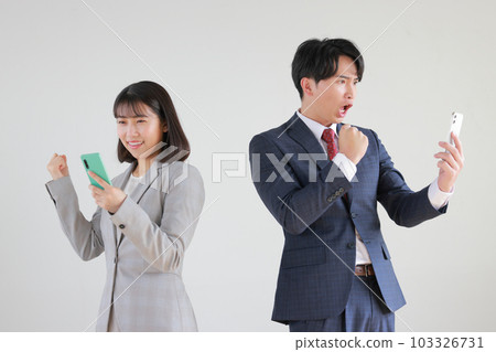 A business woman and a businessman doing a guts pose saying I saw a smartphone_1 103326731