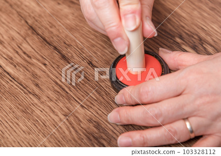 [Woman putting ink on seal] 103328112