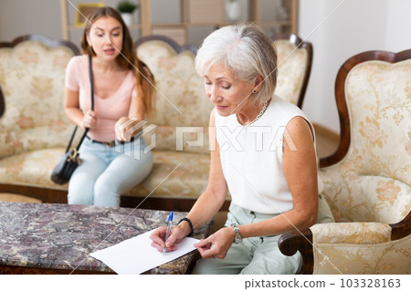 Woman realtor helping elderly woman to sign an apartment lease agreement Woman realtor helping elderly woman to sign an apartment lease agreement 103328163