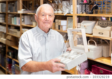 Elderly man looking for storage box for accessories Elderly man looking for storage box for accessories 103328219