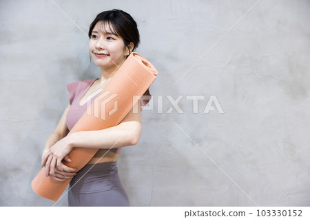 A young woman standing with a yoga mat Yoga image A young woman standing with a yoga mat Yoga image 103330152