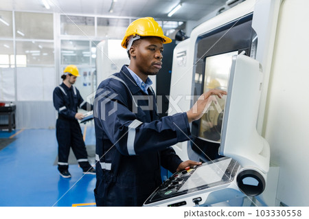Man African American engineer using computer controlling cnc machine at workshop. 103330558
