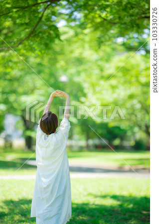 A woman stretching in a fresh green park 103330726