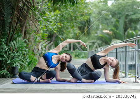 Two beautiful female sport wear exercise arm stretching yoga in garden. sport for health. Two beautiful female sport wear exercise arm stretching yoga in garden. sport for health. 103330742