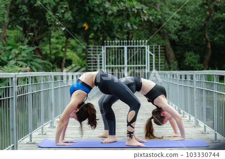 Two beautiful female sport wear exercise arm stretching yoga in garden. sport for health. 103330744