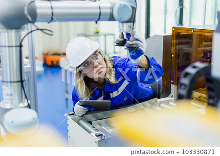 female technician engineer wear uniform with helmet safety checking automation robot arm 103330871
