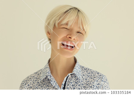 Young woman with dyed blonde hair smiles broadly and winks 103335184