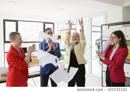 Mature manager throws up papers while colleagues applaud Mature manager throws up papers while colleagues applaud 103335192