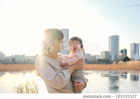母親在黃昏時抱著她的孩子 母親在黃昏時抱著她的孩子 103335327