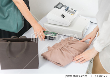 在服裝店/服裝店使用智能手機進行二維碼支付的女士 103338377