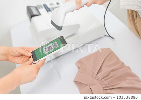 在服裝店/服裝店使用智能手機進行二維碼支付的女士 在服裝店/服裝店使用智能手機進行二維碼支付的女士 103338886
