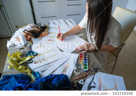 Woman draws sketches of swimwear with a pencil. Woman draws sketches of swimwear with a pencil. 103339398