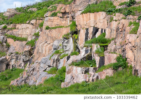 Stone cliffs overgrown with green lush grass. Stone cliffs overgrown with green lush grass. 103339462